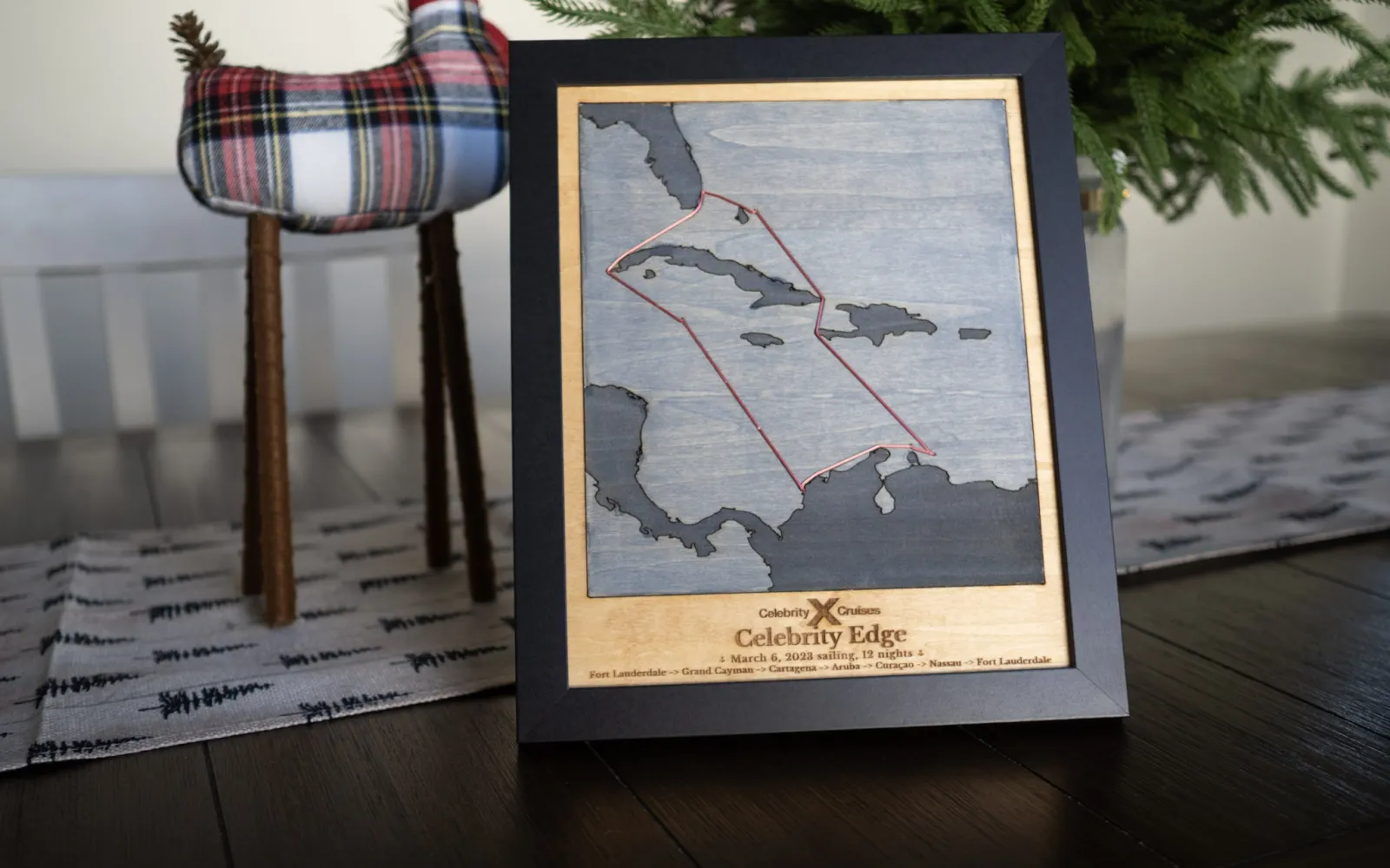 A framed wooden map of a 12-night Caribbean cruise route, laser-cut and engraved in layered, stained wood.